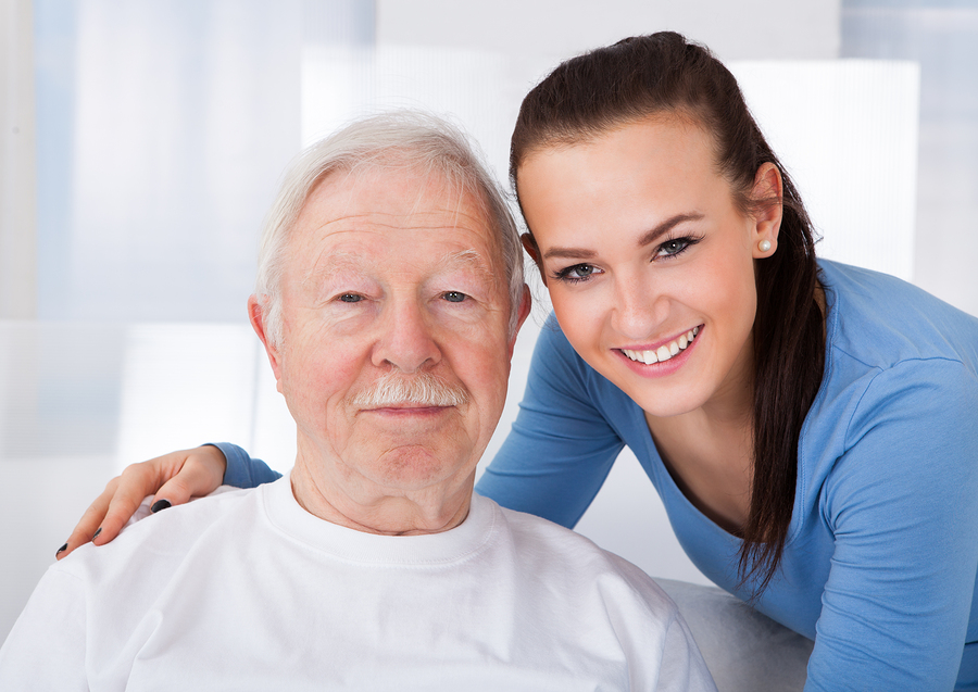 Portrait of young female caretaker with senior man at nursing home in Laguna Hills, CA